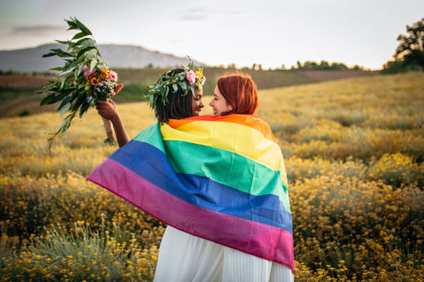 Marriage Equality Two lesbian brides dancing covered with rainbow flag gay pride symbol photos stock pictures, royalty-free photos & images