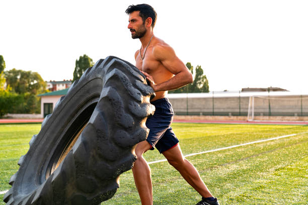 istock Young athletic man training outdoors. Athlete doing exercise with truck tire 1175788105