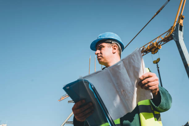 istock Building Worker is Analyzing Project Plans at the Roof of the Building Site 1175794652