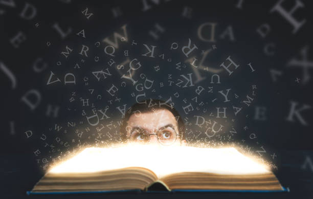 istock Glasses young man looking up magic letters with magic book in the darkness 1175798534