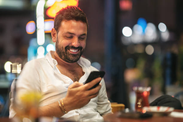 istock Young Man Using Smartphone In A Cafe At Night 1175799114