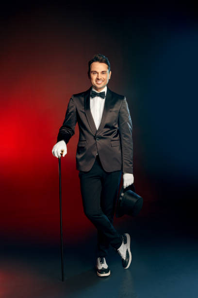 istock Professional Occupation. Showman in suit standing isolated on wall with hat and cane smiling confident full body shot 1175803463