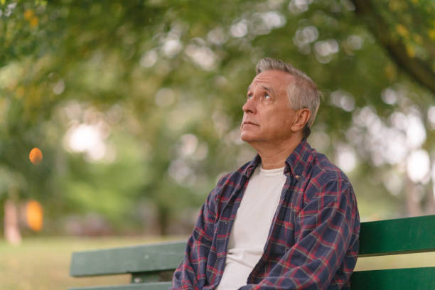 istock Contemplative senior man sitting on park bench 1175803680