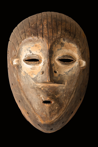 An African ceremonial mask carved in wood with white pigment signifying anti-witchcraft powers, isolated on black.