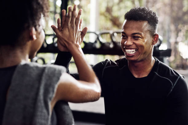 See what happens when you don't give up Shot of a young man and woman giving each other a high five at the gym fitness trainer stock pictures, royalty-free photos & images