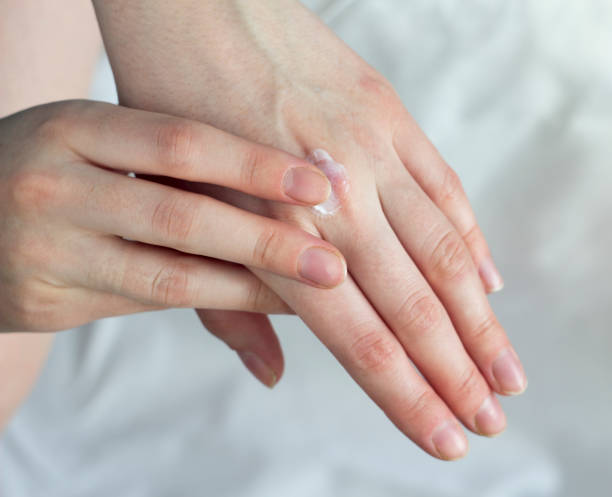 istock A girl smears a hand cream on a white background 1175838653