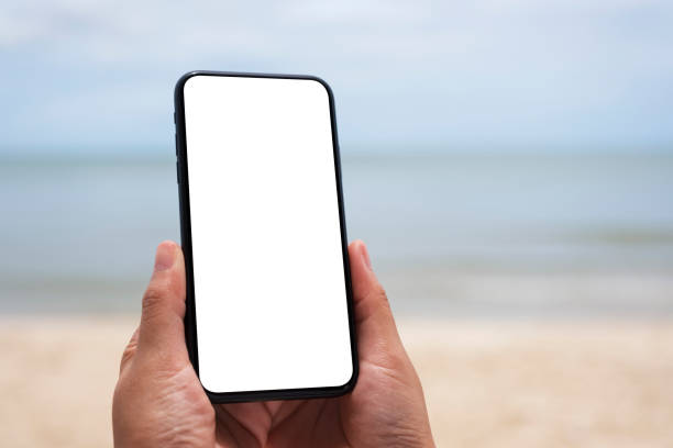 istock hands holding black mobile phone with blank desktop screen by the sea 1175838812