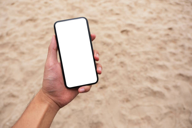 istock a man's hand holding black mobile phone with blank desktop screen while standing on beach chair 1175838815