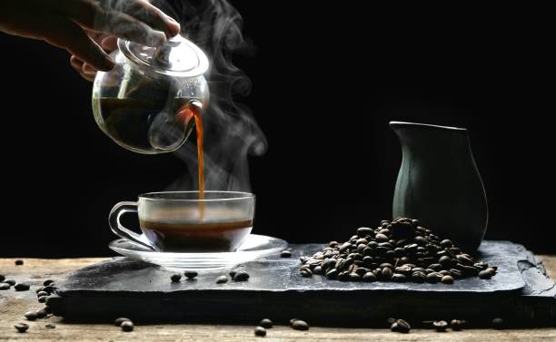istock Pouring hot tea into glass coffee cup in black background 1175840140