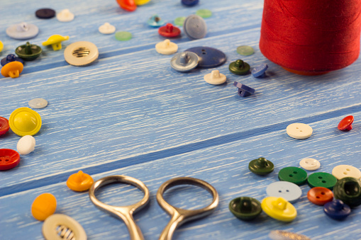 scissors, buttons and threads on a wooden background