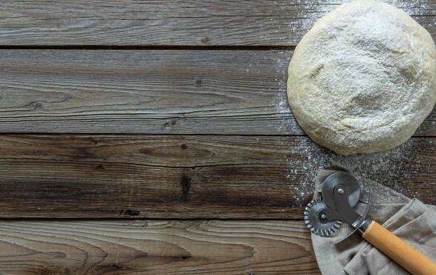 istock The dough is sprinkled with flour on a wooden background. 1175844043