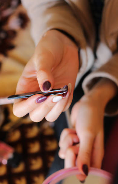 istock young woman with tweezers and mirror in hand 1175845665