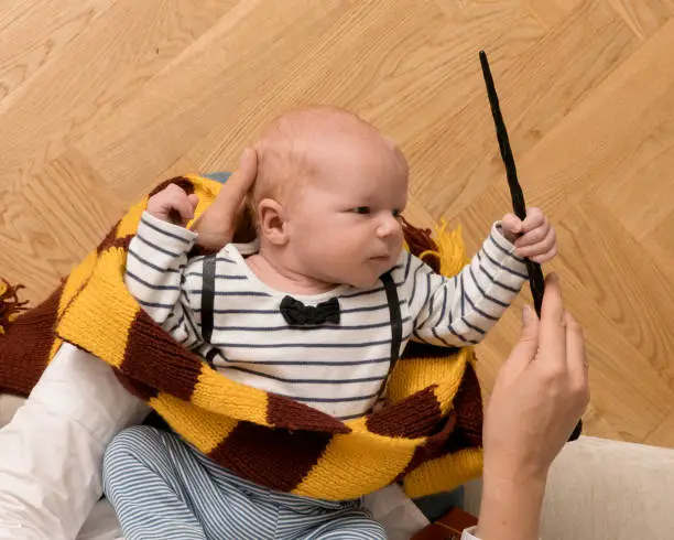 Little newborn baby boy like in a magic book in halloween time. Magic wand, and scarf.