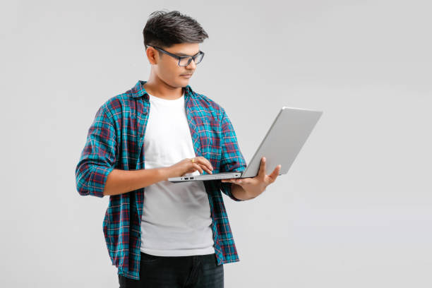 istock handsome Indian / Asian male student using laptop, isolated on white background 1175850864