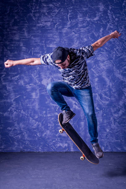 istock Skateboarder performing a high jump on blue background. Ollie. 1175852277