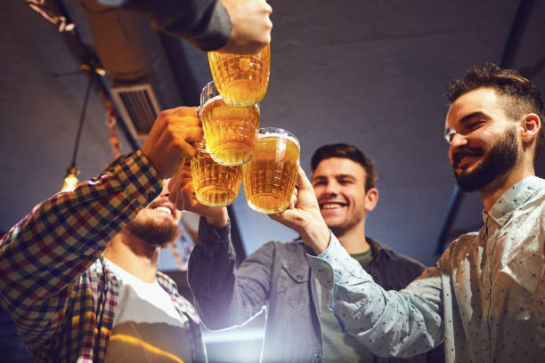 istock Young people clink glasses with beer in a bar. 1175853330