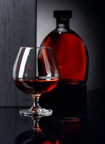 istock Glass and bottle of brandy on a black reflective background. 1175859944