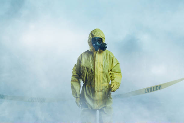 Worker in protective suit Worker wearing yellow protective suit walking in fog gas mask stock pictures, royalty-free photos & images