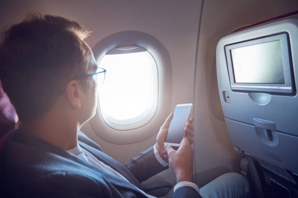 istock Man using cellphone to take photos through the airplane window. 1175862966