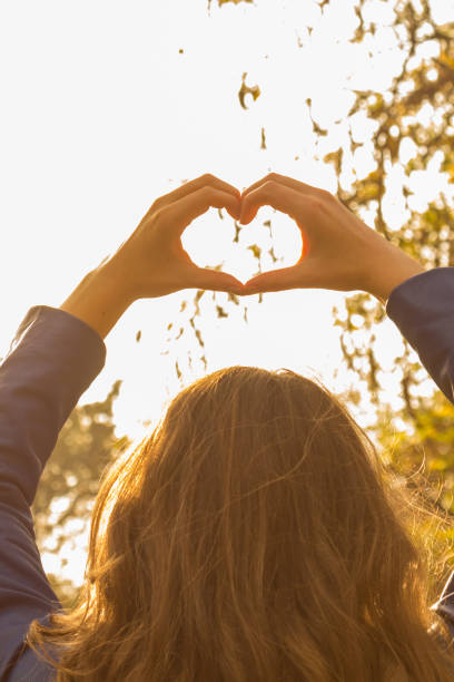 mujer joven haciendo corazón - símbolo de forma con sus manos. - heart shape loneliness women praying fotografías e imágenes de stock