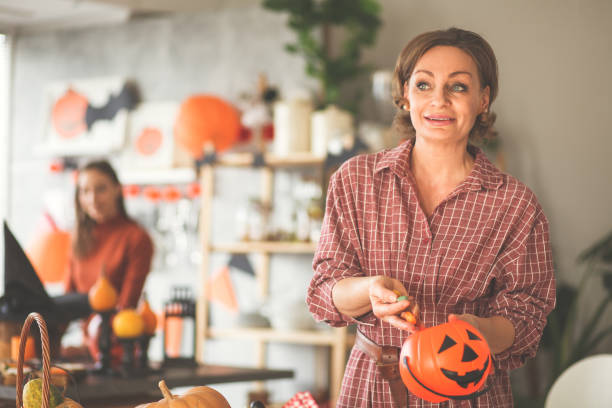 istock Focus on mother putting candy into a plastic pumpkin bowl 1175865647