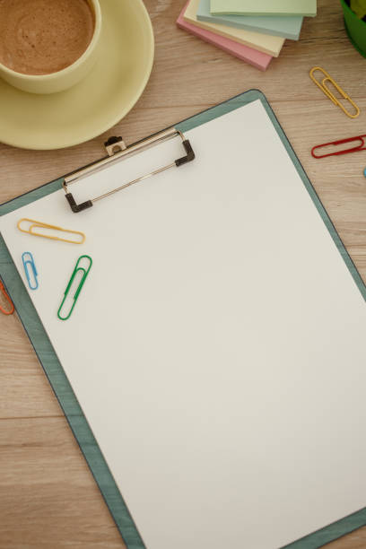Clipboard with blank paper, paper clips and coffee on a desk