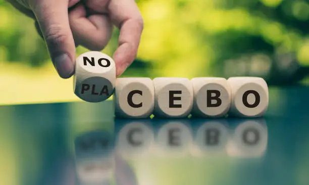 Nocebo or placebo? Hand turns a cube and changes the word "placebo" to "nocebo", or vice versa.