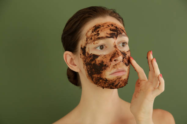 istock Woman exfoliating face with a coffee scrub, studio shot. 1175868581