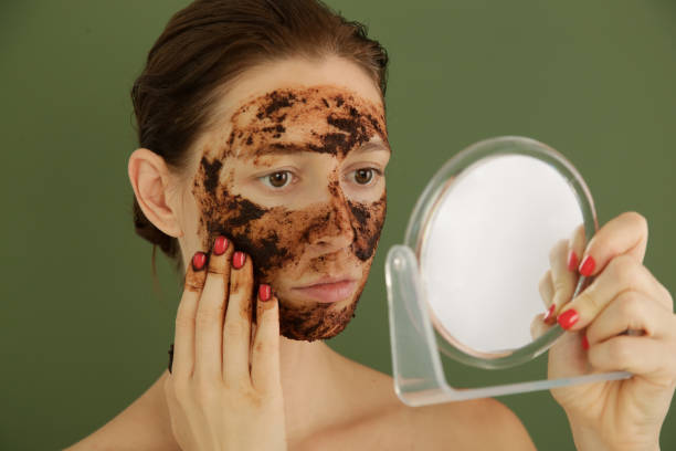 istock Woman applying coffee scrub in front of the mirror, studio shot. 1175868730