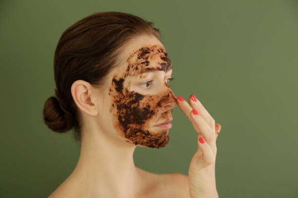 istock Woman exfoliating face with a coffee scrub, studio shot. 1175868732