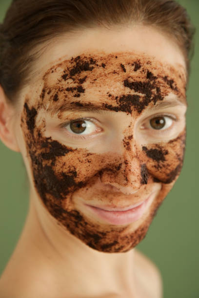 istock Woman exfoliating face with a coffee scrub, studio shot. 1175868878