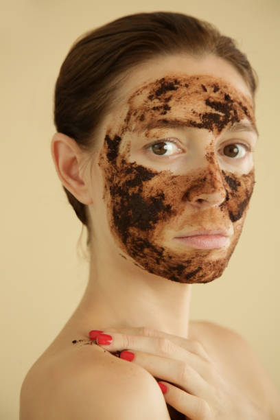 istock Woman exfoliating face with a coffee scrub, studio shot. 1175868882