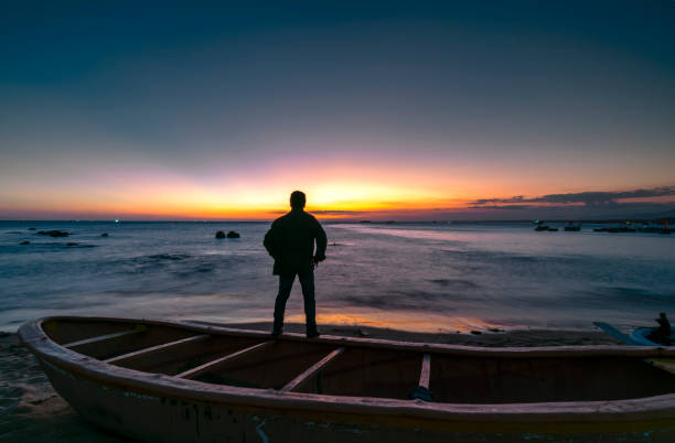 Silhouette traveler man standing in front of the sea watching the sunset Silhouette traveler man standing in front of the sea watching the sunset basket boat stock pictures, royalty-free photos & images