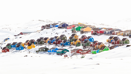 Multiple colorful Inuit houses and cottages on the hill covered in snow, Aasiaat city, Greenland
