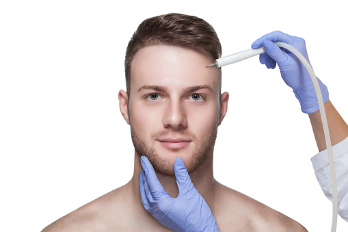 Men's cosmetology. Beautician makes a man a procedure to remove acne from his face.