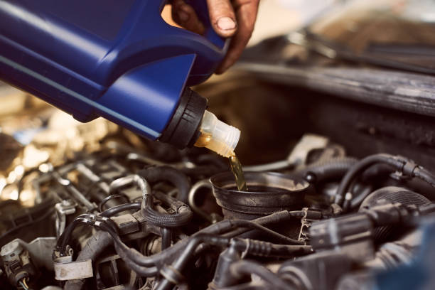istock Engine oil changing and maintenance gear car engine in auto service workshop. Close up of pouring motor oil into engine 1175875298