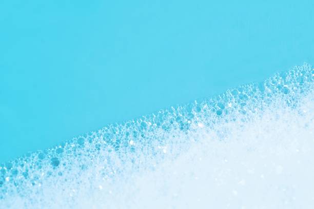 Backgrounds of blue foam soap bubbles on blue background. Laundry detergent, suds textured pattern. White soap suds macro view.