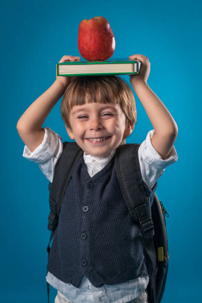 istock Happy little school boy Carry Book Apple on Head 1175882827