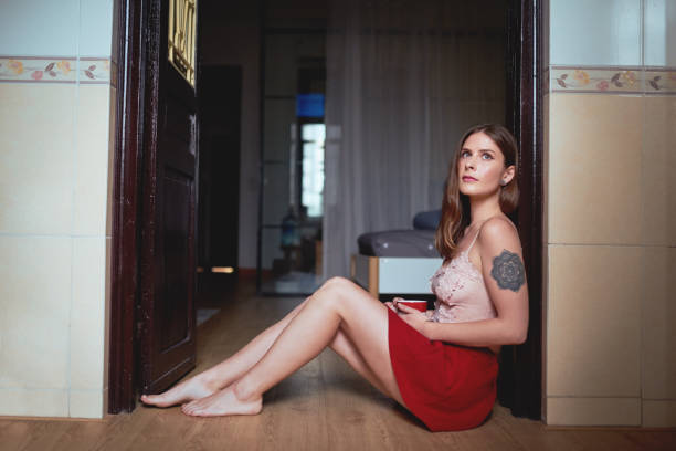 Full length shot of an attractive young woman sitting on the floor and drinking coffee inside her apartment