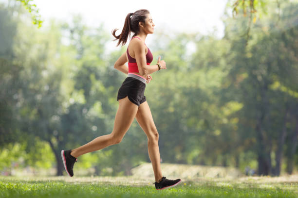 young female athlete jogging outdoors - running women jogging profile imagens e fotografias de stock