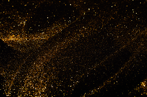 Splash of golden sparkles on black background.