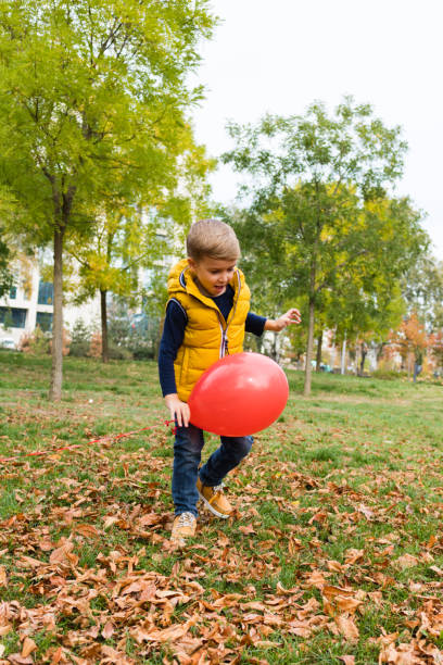 istock Happy kid playing with balloon in autumn day. 1175886475