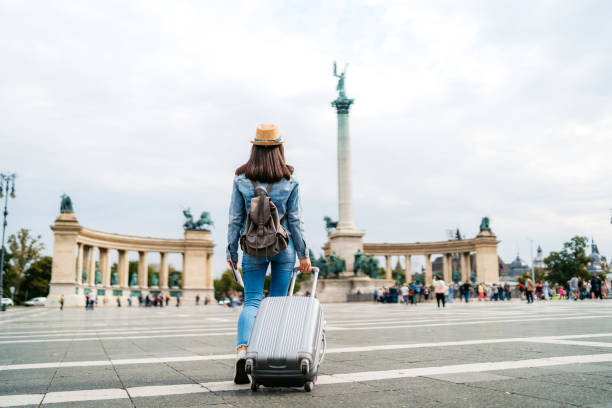Tourist woman visiting Budapest Young caucasian slim tourist woman visiting Budapest. Walking over Heroes' Square with luggage and map. wheeled luggage stock pictures, royalty-free photos & images