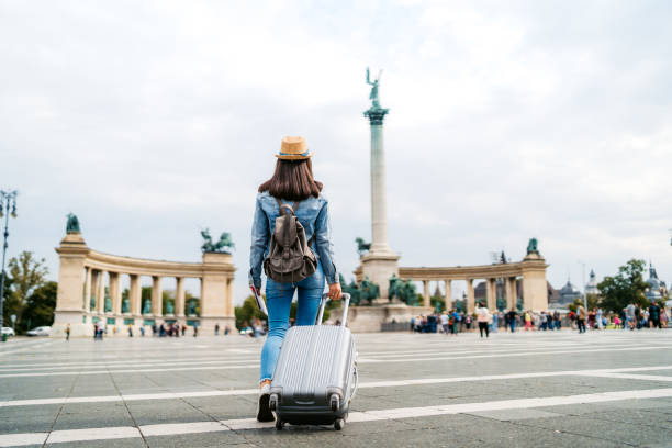 Tourist woman visiting Budapest Young caucasian slim tourist woman visiting Budapest. Walking over Heroes' Square with luggage and map. exchange student stock pictures, royalty-free photos & images