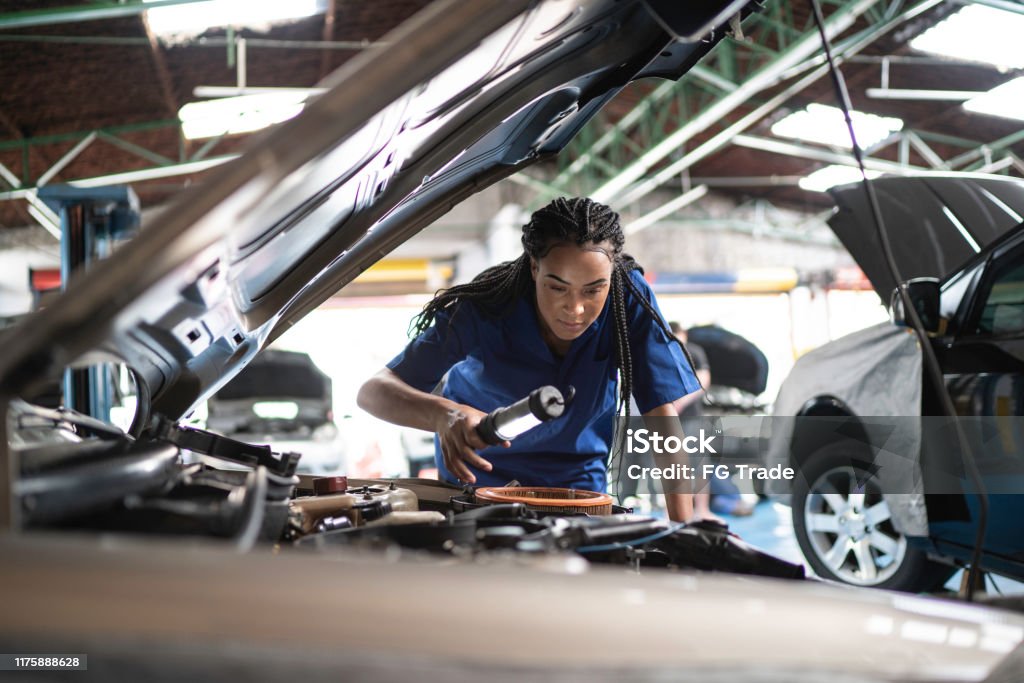 Kvinna reparera en bil i Auto Repair Shop - Royaltyfri Bil Bildbanksbilder