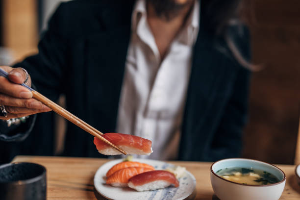 An assortment of Japanese sushi rolls and sashimi, beautifully arranged on a black plate. Captured in Tokyo, Japan