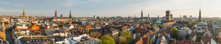 Aerial panoramic view across the rooftops and spires of central Copenhagen at sunset, Denmark.