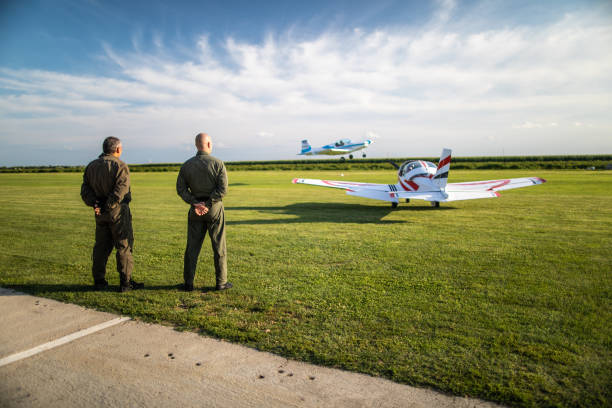 An old white biplane in the air.