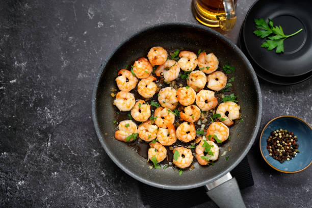 top view of fried prawns in a pan on black table - shrimp pan cooking prepared shrimp imagens e fotografias de stock