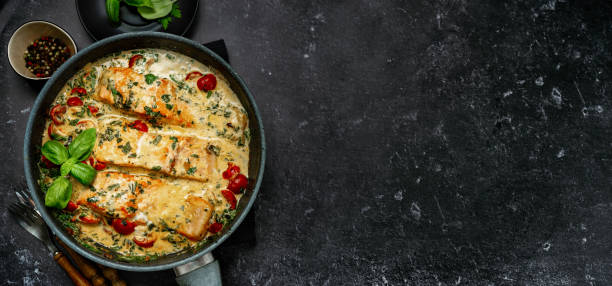 istock Banner with delicious tuscan cream salmon with spinach in a black pan 1175892964